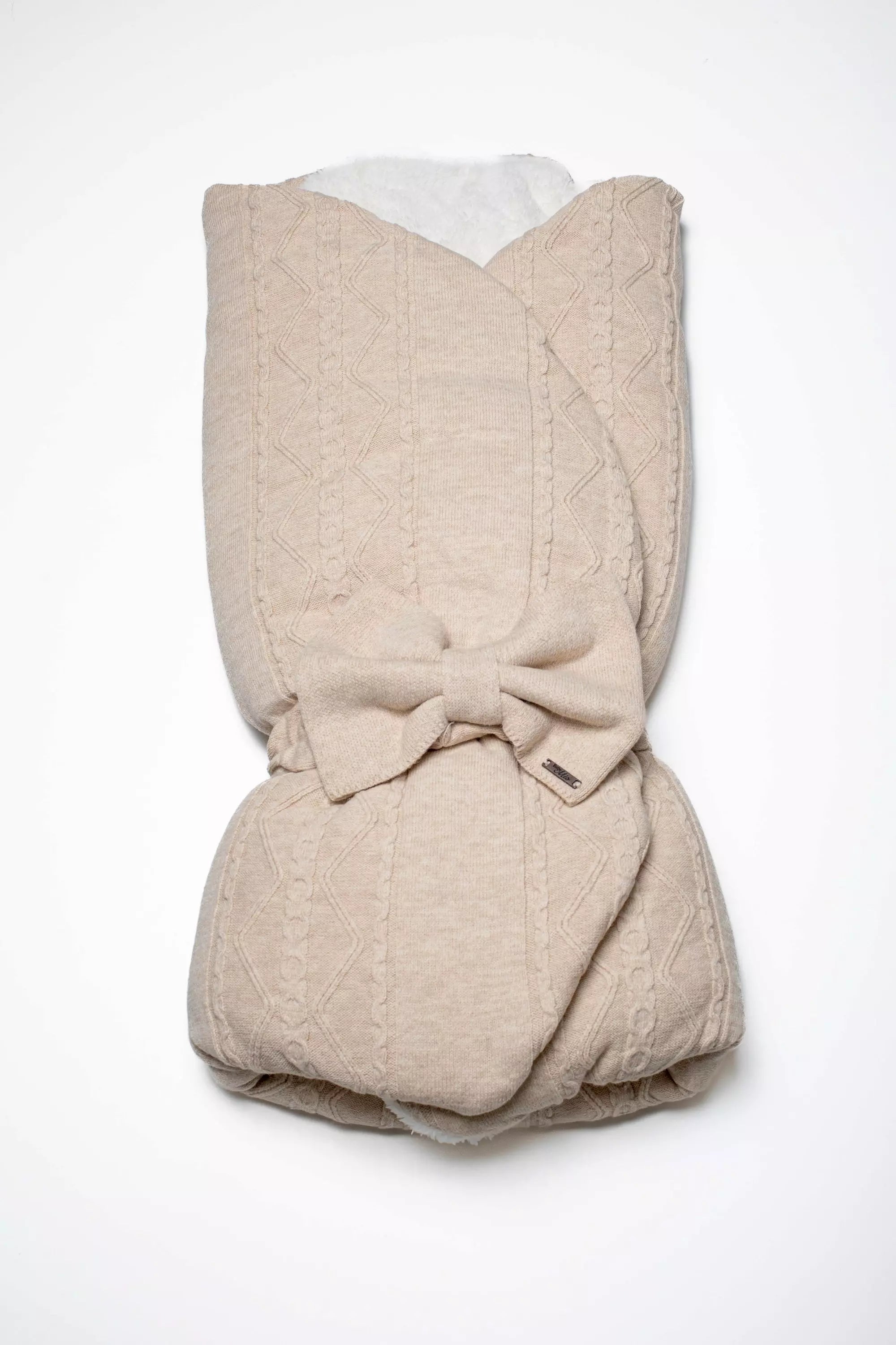 Warme Baby Einschlagdecke aus Strick in Beige mit Zopfmuster und großer dekorativer Schleife. Ideal für Kinderwagen und Babyschale.