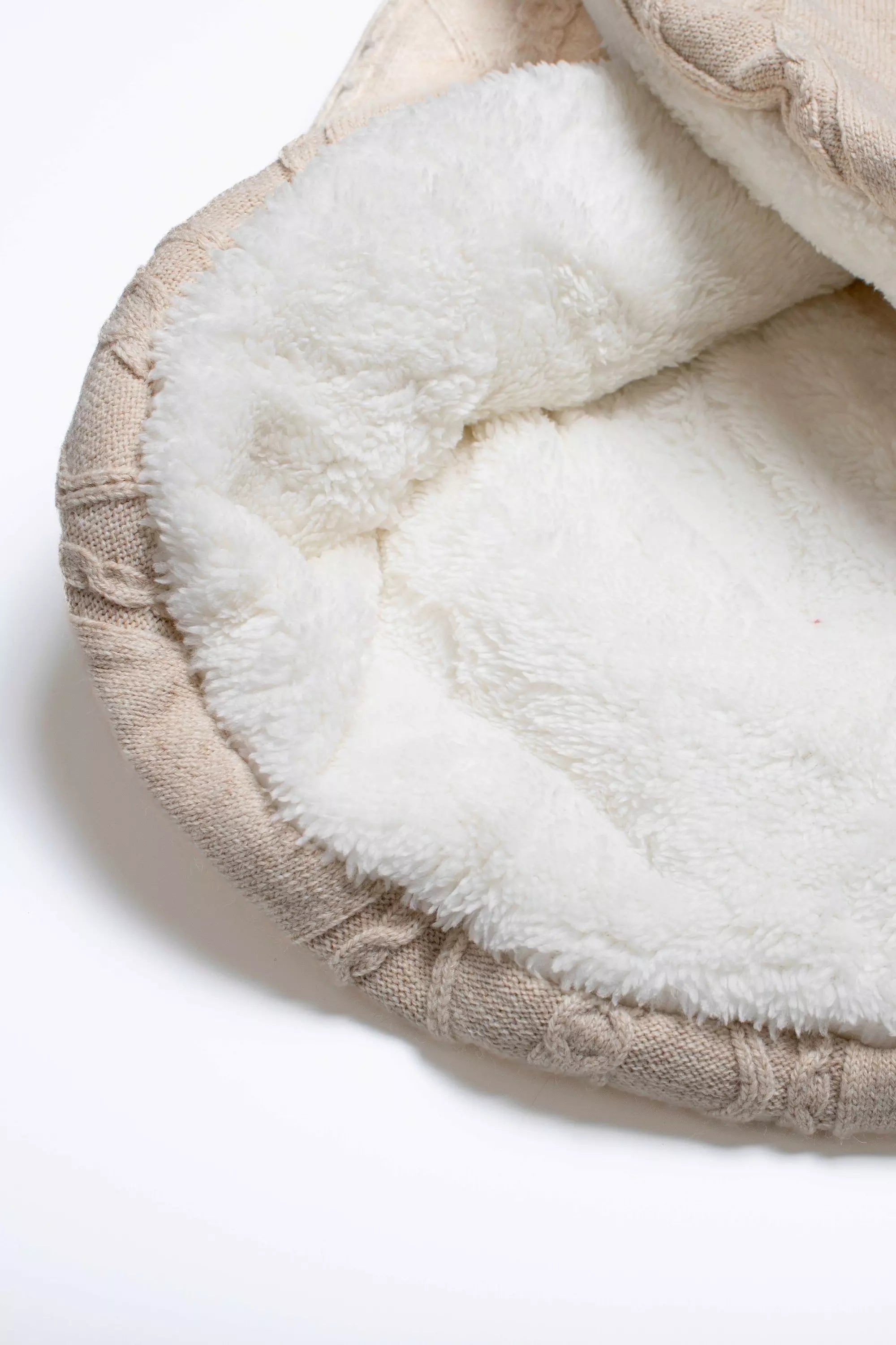 Detailansicht des weichen, cremefarbenen Teddyfutters der beige gestrickten Baby Einschlagdecke.