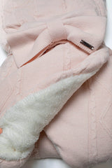 Detailansicht der rosa Strick-Einschlagdecke mit Schleife und Blick auf das weiche, weiße Teddyfutter.