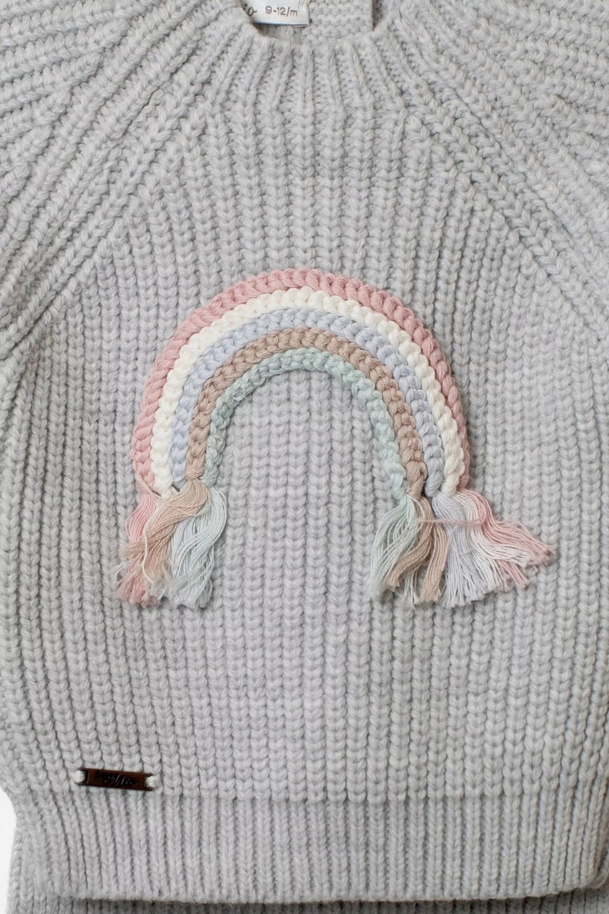 Nahaufnahme Strickpullover grau mit pastellfarbener Regenbogen-Applikation