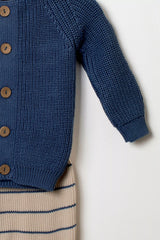 Detailansicht des Ärmels und des Strickmusters des dunkelblauen Baby Cardigans kombiniert mit der gestreiften Strickhose.