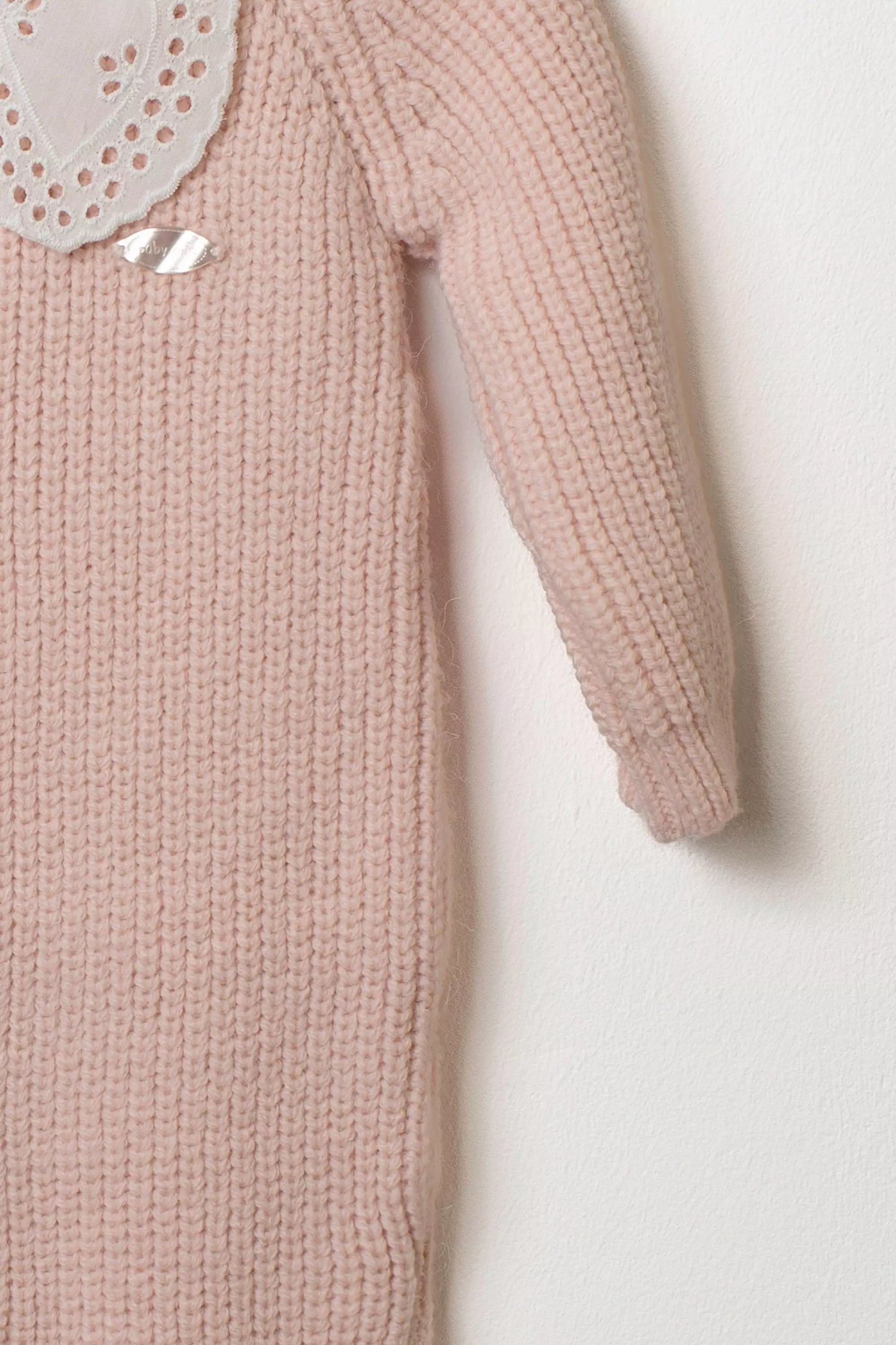 Detailansicht des Ärmels und des Lochstickerei-Kragens des rosa Baby Strick-Overalls.