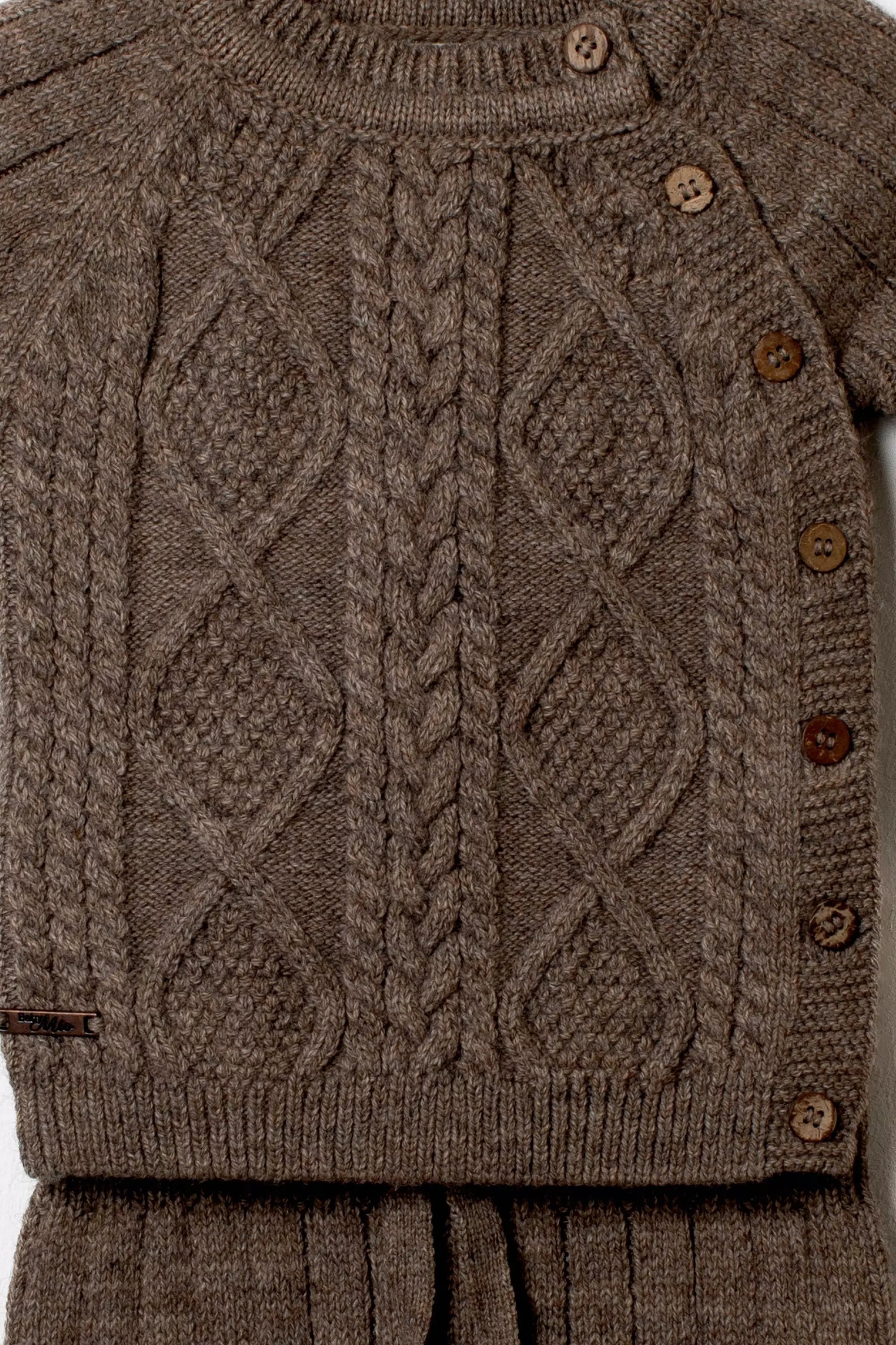 Nahaufnahme des dunkelbraunen Baby Strickpullovers mit detailliertem Zopf und Rautenmuster sowie Holzknopfleiste an der Schulter