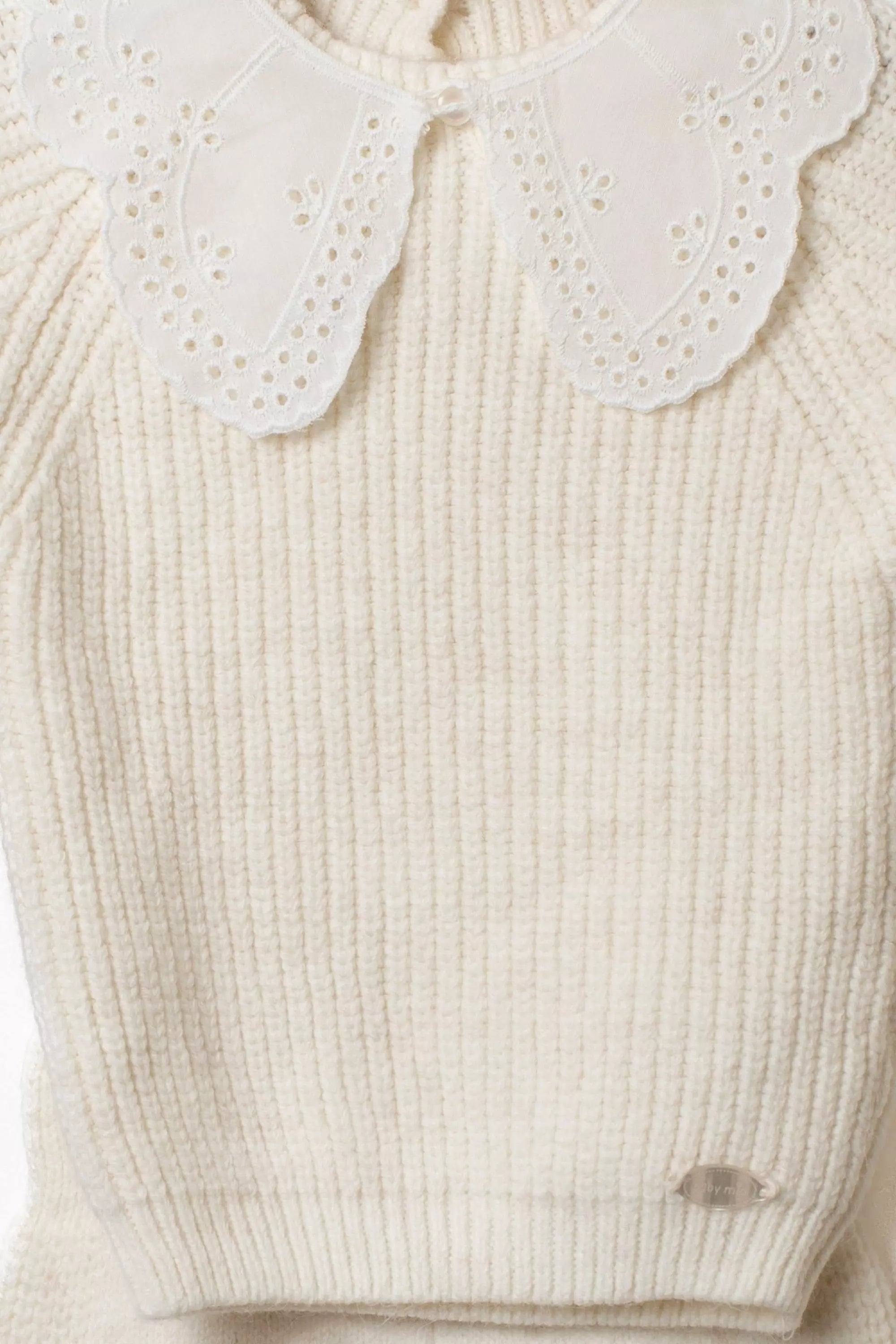 Nahaufnahme des cremefarbenen Baby Strickpullovers mit breitem Rippstrickmuster und weissem besticktem Bubikragen