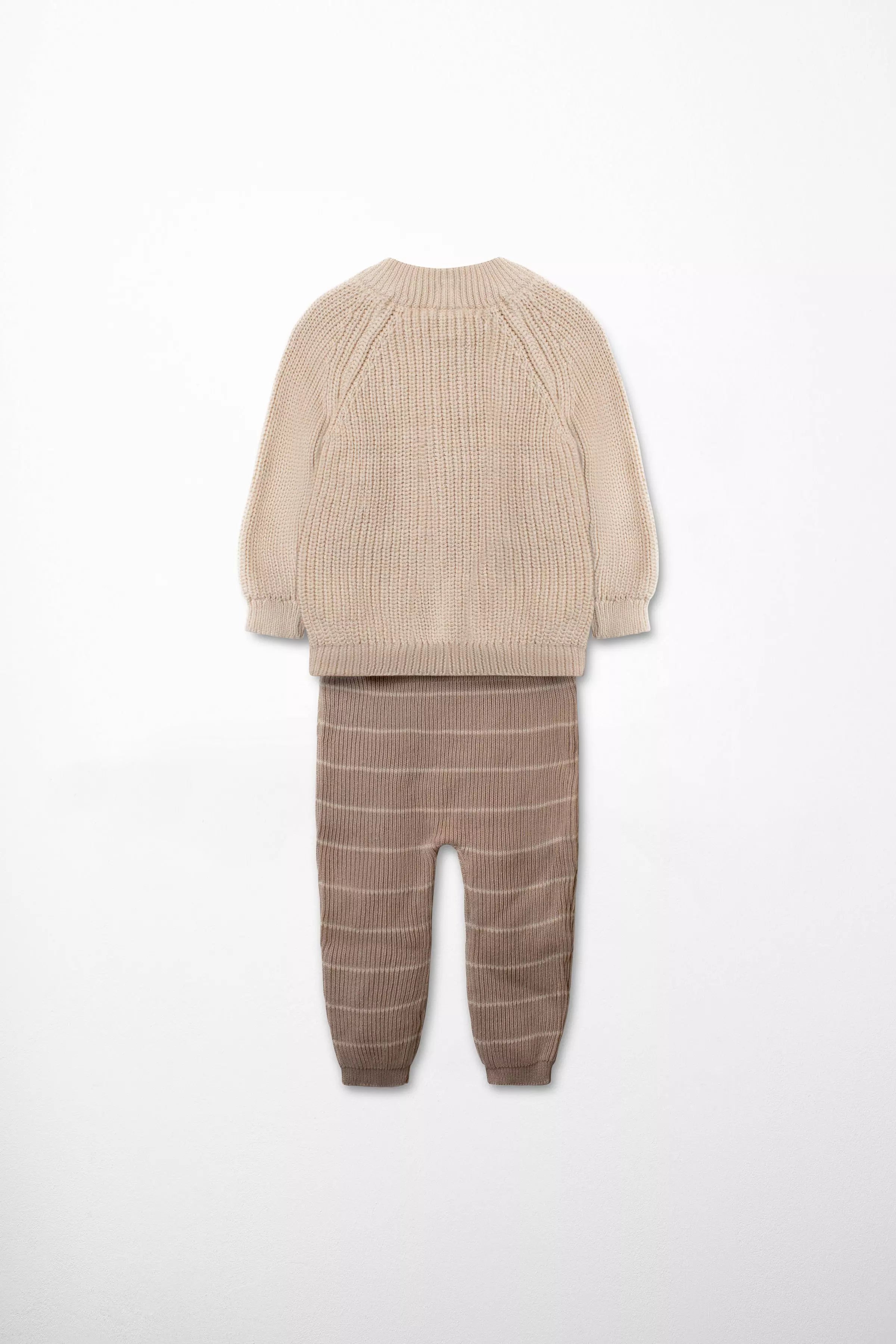 Rückansicht des warmen Baby Strick-Sets, bestehend aus beigefarbenem Cardigan und braun-gestreifter Hose.