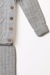 Nahaufnahme des Ärmels des grauen Strickpullovers mit Knopfleiste aus Holzknöpfen und Rippstrick der Hose