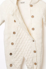 Nahaufnahme des geöffneten cremefarbenen Baby Strick-Overalls mit Zopfmuster, weichem Teddyfutter und rustikalen Holzknöpfen.