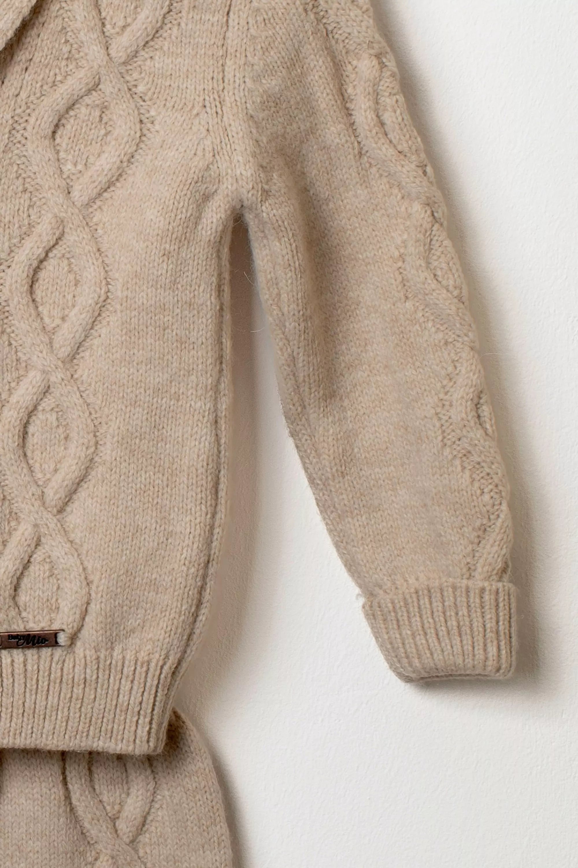 Detailaufnahme Strickjacke beige Zopfmuster Ärmel Saum Etikett