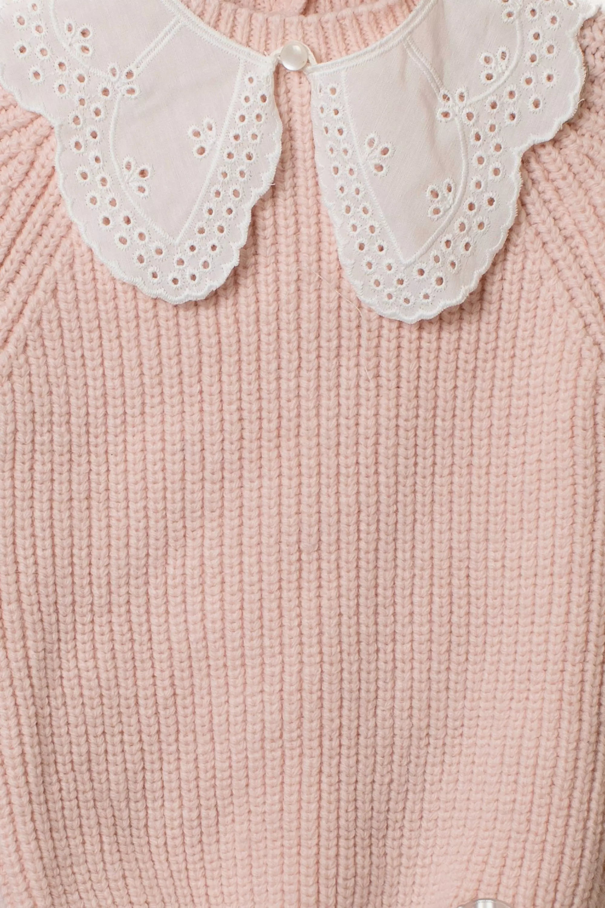 Detailansicht des weißen Lochstickerei-Kragens auf dem rosa Baby Strick-Overall.