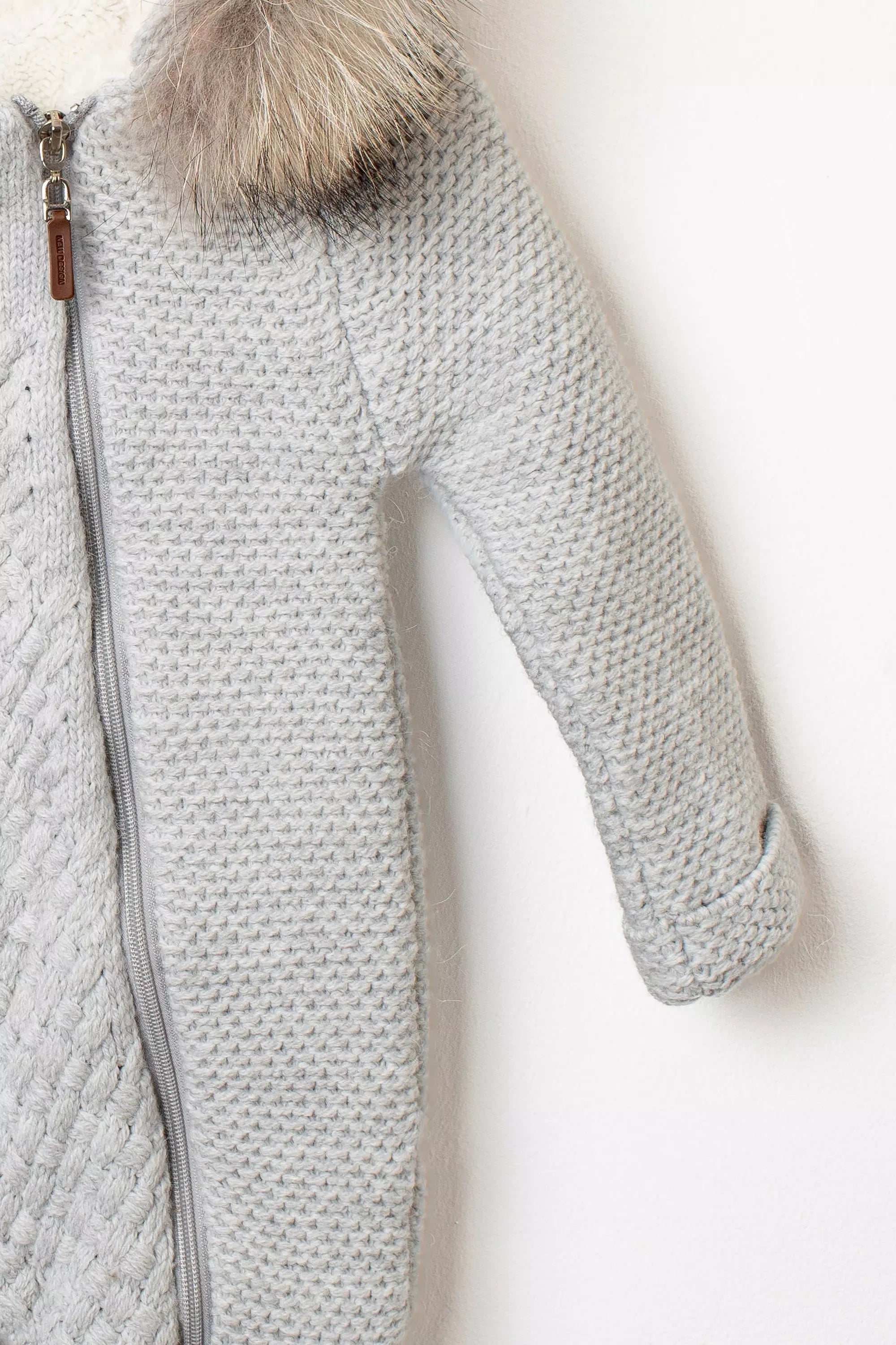 Detailaufnahme des Ärmels und Reißverschlusses eines grauen Stramplers