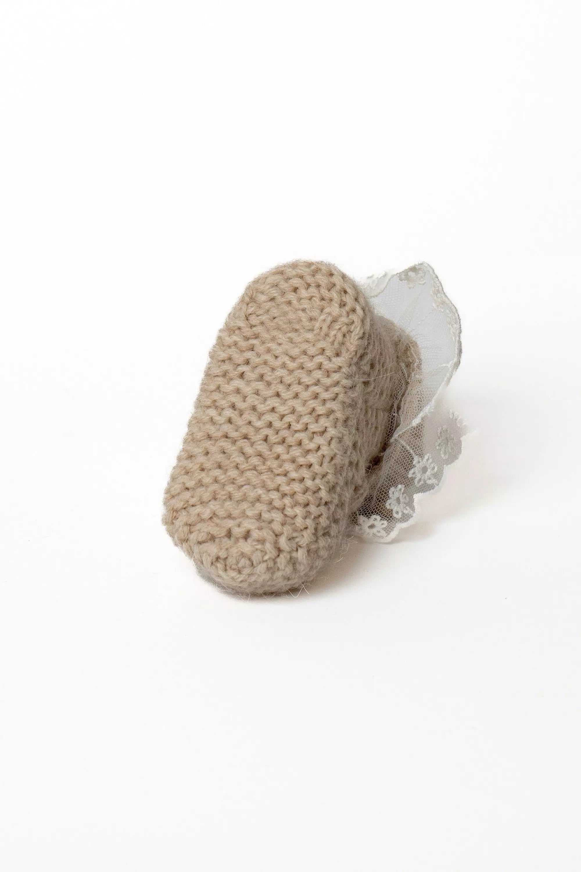Ansicht der Sohle eines braunen Babystrickschuhs aus Feinstrick mit kleiner Spitzenborte.
