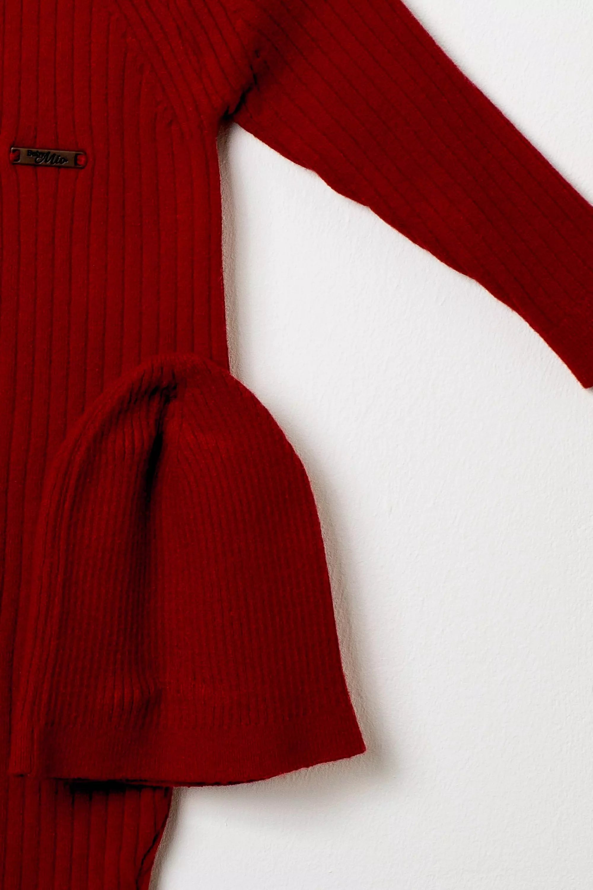 Nahaufnahme der gerippten roten Baby-Mütze, passend zum Strick-Overall