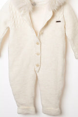 Nahaufnahme der Knopfleiste des weißen Strick-Overalls und des Fellbesatzes an der Kapuze