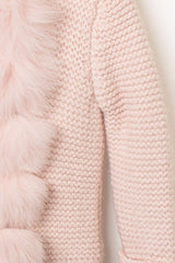 Nahaufnahme des Strickmusters der zartrosa Babyjacke, detailreich gearbeitet, mit weichem rosa Pelzbesatz