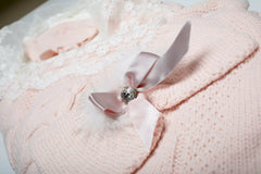 Nahaufnahme der dekorativen rosa Satinschleife mit Strassstein auf dem gestrickten Baby Schlafsack