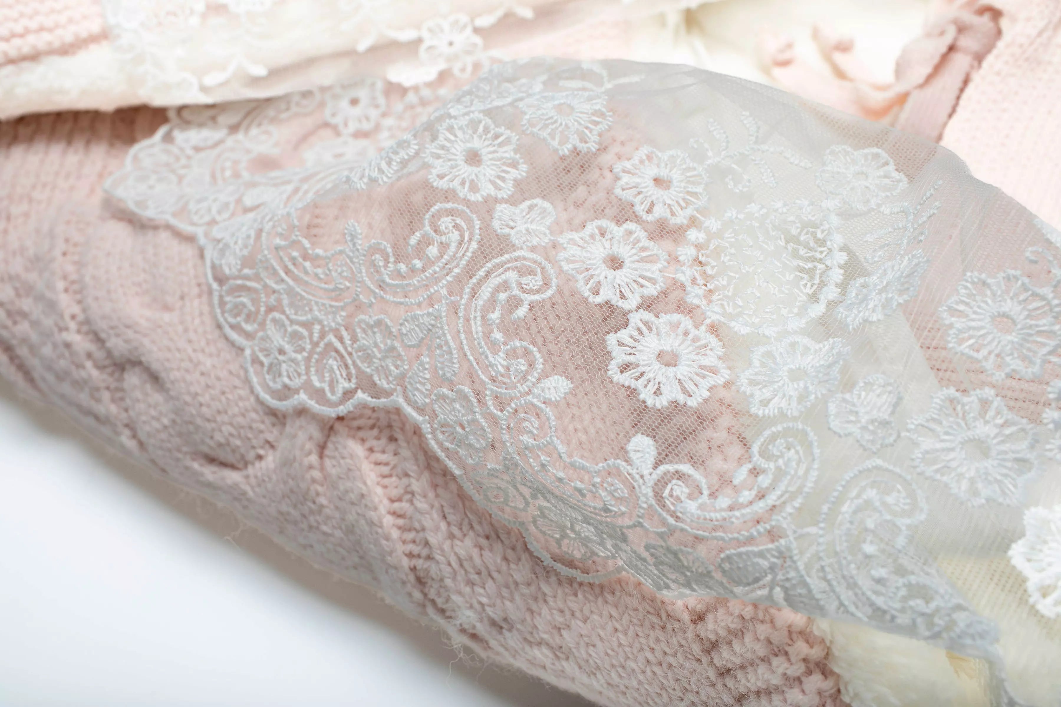 Nahaufnahme der feinen weißen Spitze und des gestrickten rosa Materials des eleganten Baby Schlafsacks