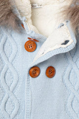 Nahaufnahme der Knopfleiste der hellblauen Baby-Strickjacke, mit Zopfmuster, rustikalen Holzknöpfen und flauschigem weißem Innenfutter