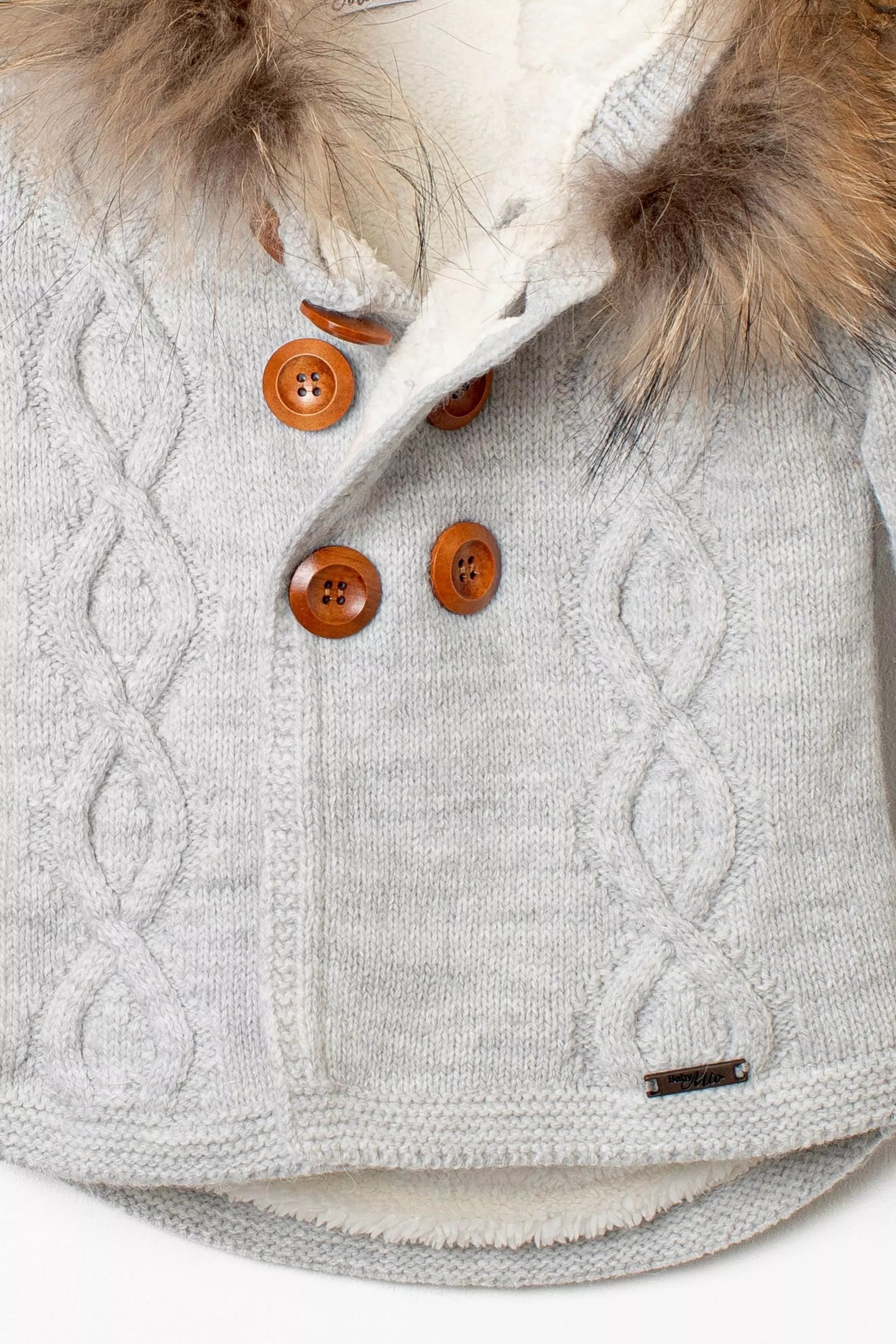 Nahaufnahme der Knopfleiste der grauen Baby-Strickjacke, mit Zopfmuster, großen Holzknöpfen und flauschigem Innenfutter
