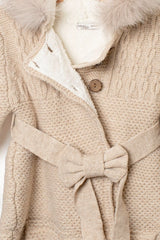 Nahaufnahme der Vorderseite des beigen Babymantels mit Gürtelschleife, Knopfverschluss und Innenfutter
