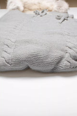 Detailaufnahme der gestrickten Zopfmuster-Struktur an der Unterseite des Baby-Schlafsacks in Grau