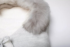 Nahaufnahme des weichen, grauen Fellrands und des flauschigen weißen Innenfutters des Baby-Schlafsacks