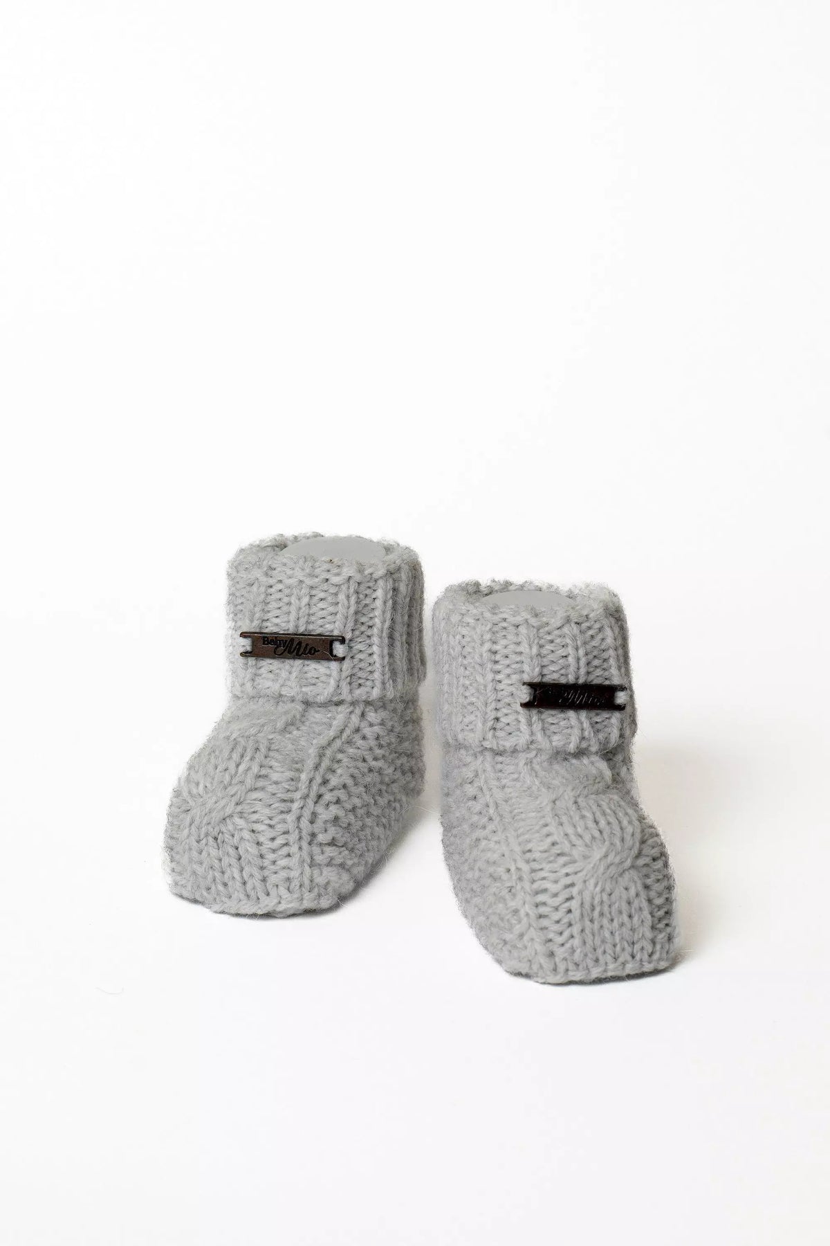 Paar warme graue Baby Strickschuhe mit Zopfmuster und Label, gestrickte Booties