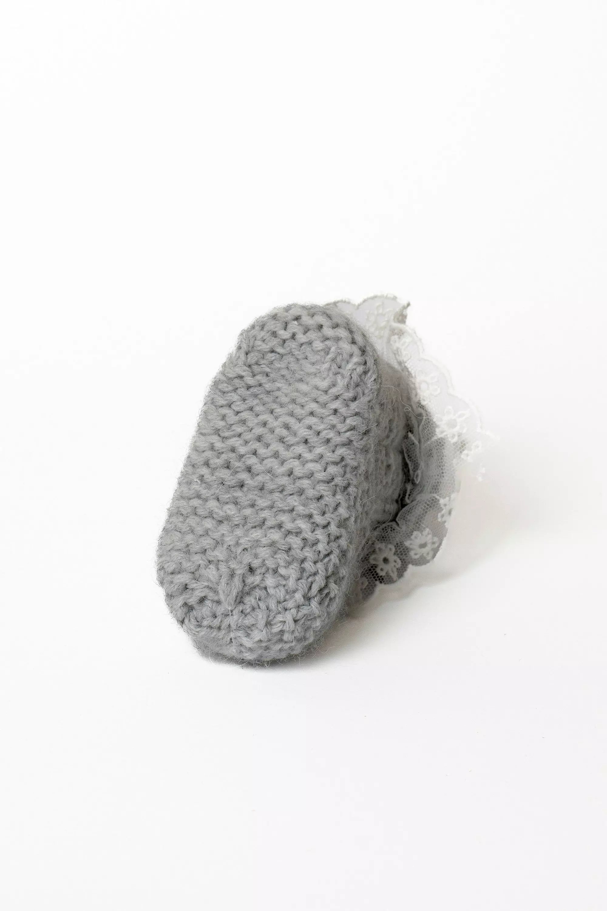 Ansicht der Sohle eines grauen Babystrickschuhs, die das dicke Grobstrickmuster für Wärme zeigt.