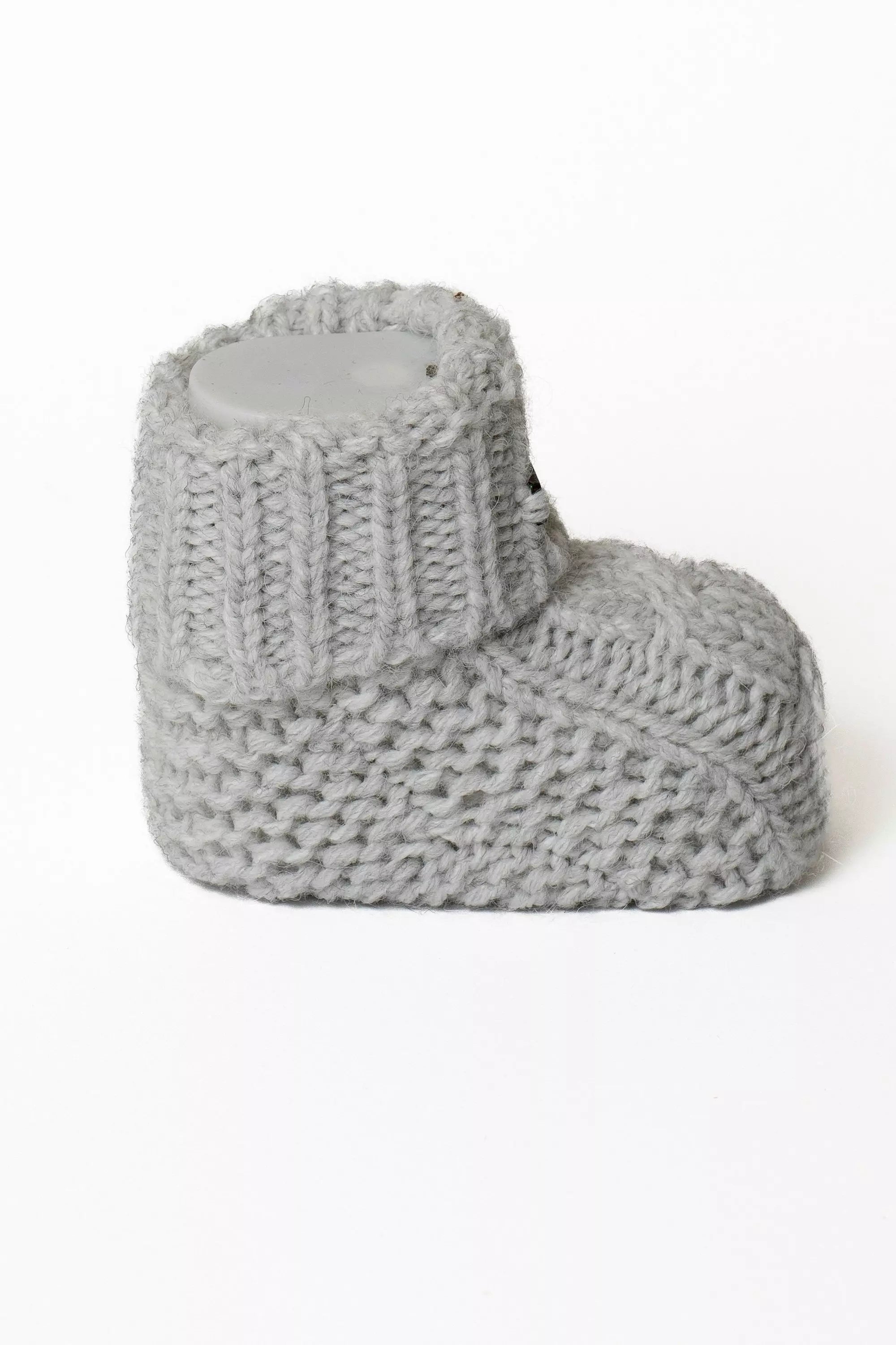 Einzelner grauer Baby Strickschuh, Seitliche Ansicht mit umgeschlagenem Rippstrickbund
