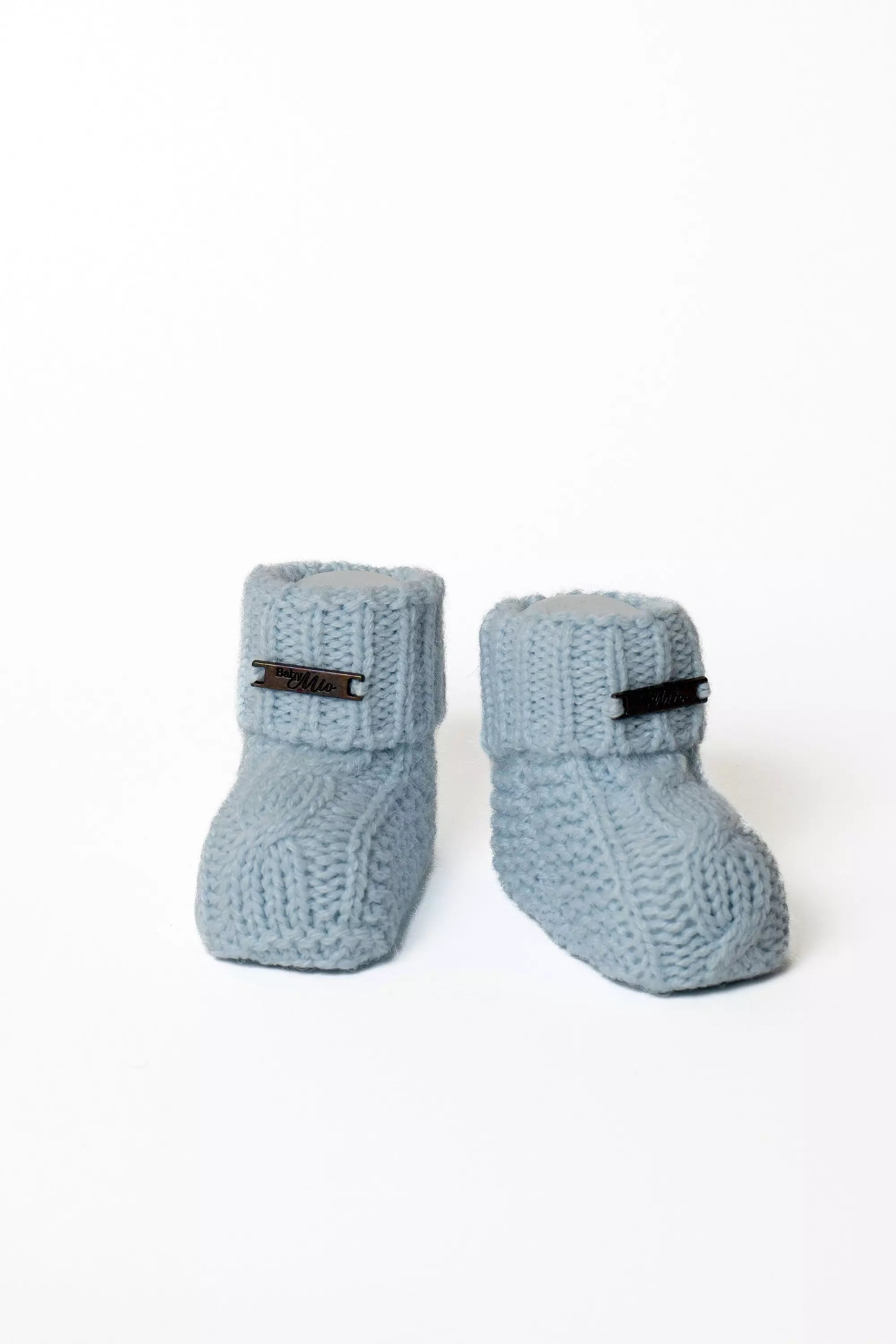 Paar hochwertige hellblaue Baby Strickschuhe mit umgeschlagenem Bund und Label, Zopfmuster
