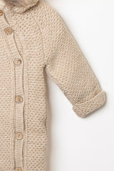 Detailansicht des Ärmels und der Knopfleiste des beigen Baby Strick-Schneeanzugs mit Holzköpfen und umgeschlagenem Strickbündchen.