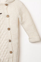 Detailansicht des Ärmels und der Knopfleiste des weißen Baby Strick-Schneeanzugs mit Zopfmuster und Holzknöpfen.