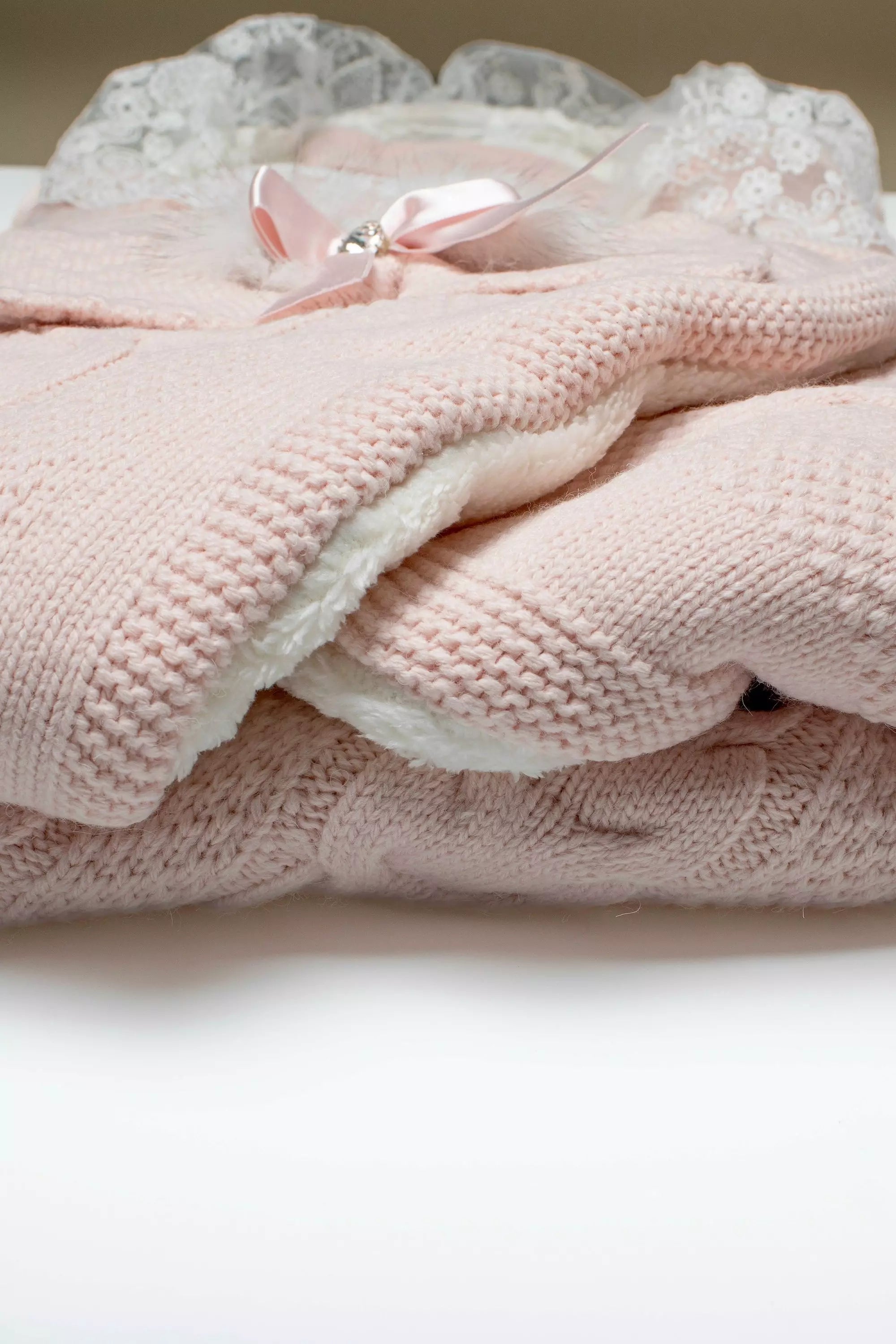 Detailansicht des rosa Strick-Außenmaterials mit Zopfmuster und dem dicken, weißen Teddyfell-Innenfutter