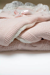 Detailansicht des rosa Strick-Außenmaterials mit Zopfmuster und dem dicken, weißen Teddyfell-Innenfutter