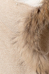 Nahaufnahme der Kapuze des beigen Baby-Strickoveralls, die das detailreiche Strickmuster und den braunen Fellbesatz zeigt.