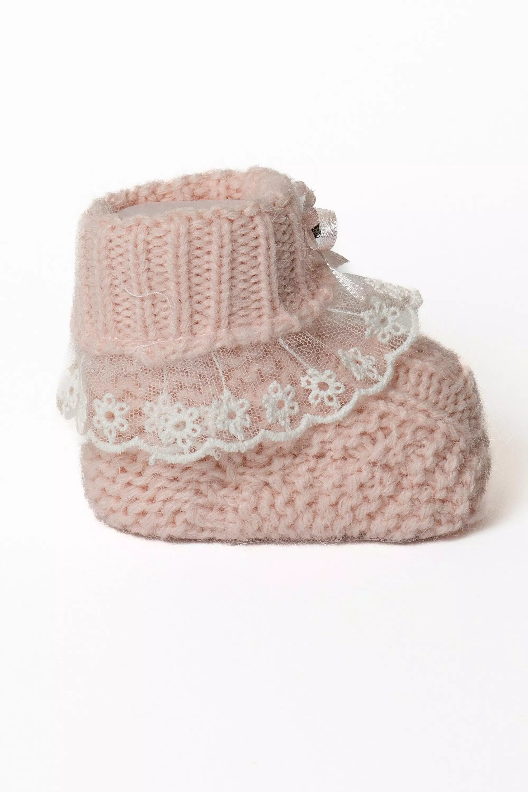 Detailaufnahme eines einzelnen rosa Babystrickschuhs, zeigt die Struktur des Grobstricks und die weiße Blüten-Spitze.