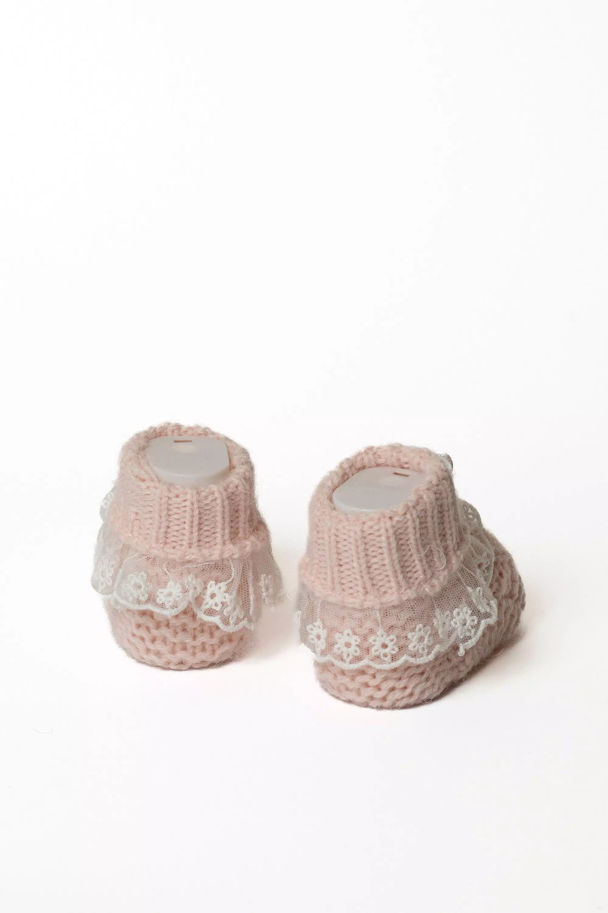Paar rosa gestrickte Babyschühchen von der Seite, verziert mit einem breiten Spitzenrand.