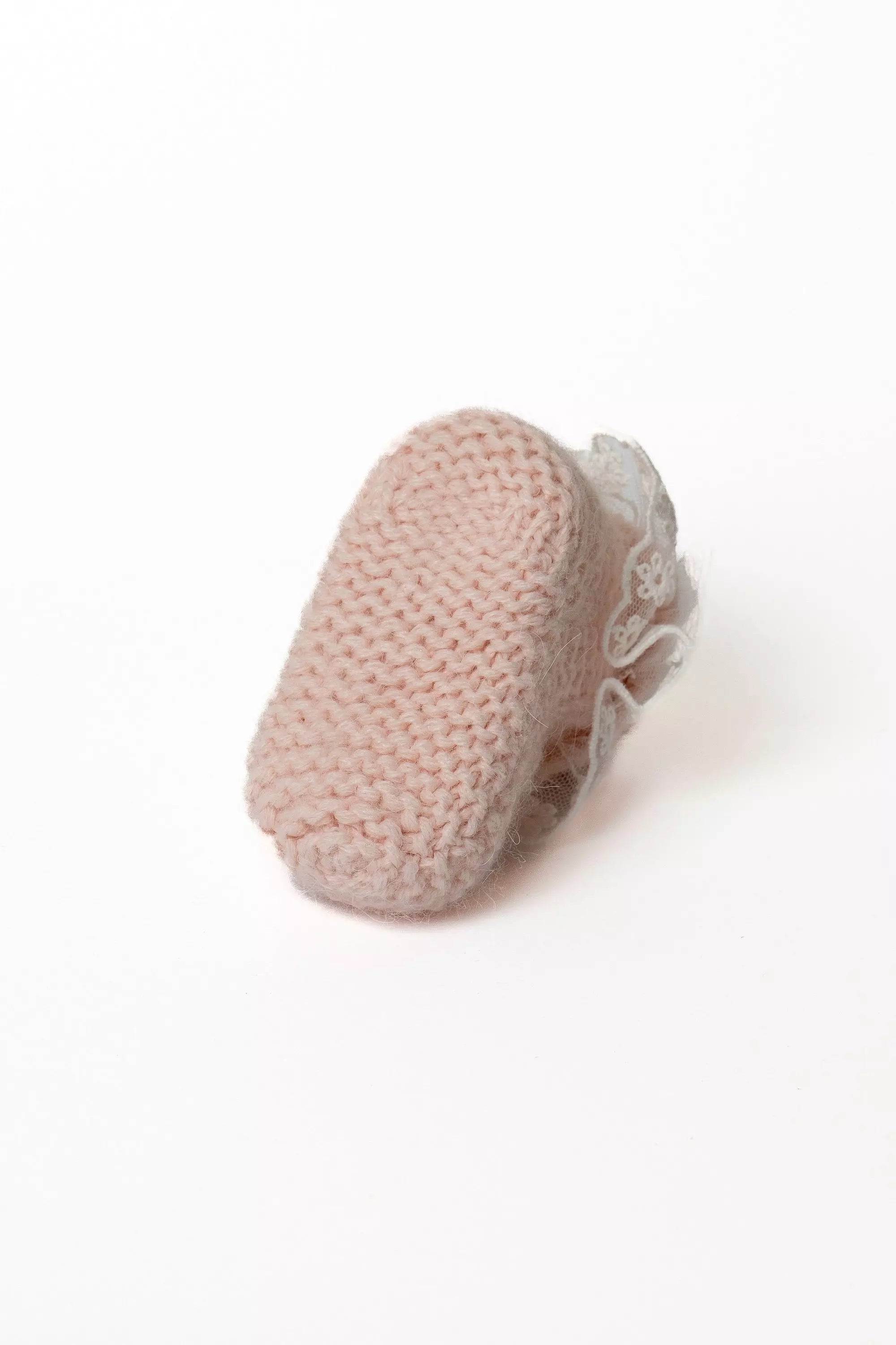 Ansicht der Sohle eines rosa Babystrickschuhs, die die dichte Strickstruktur zeigt.