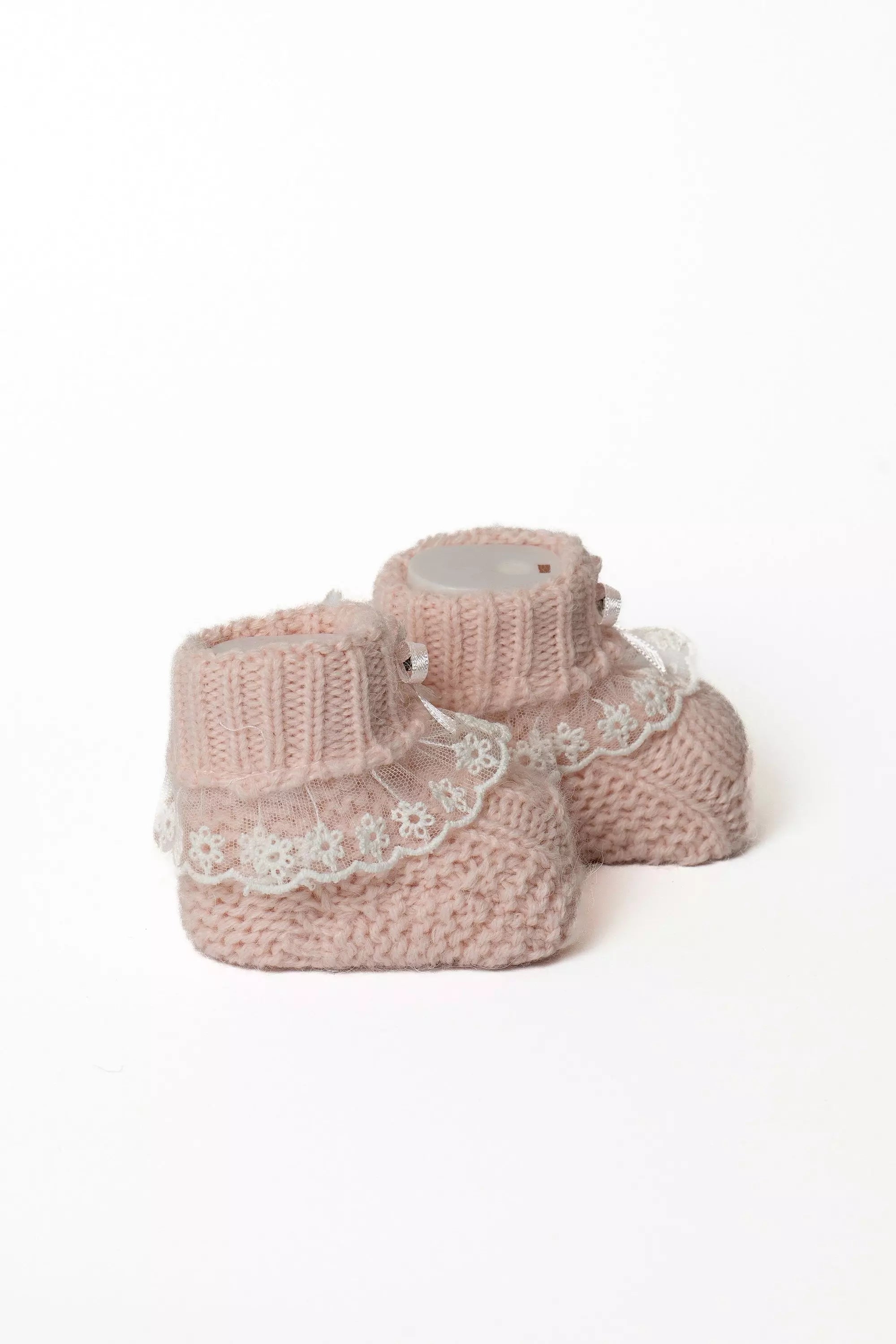 Paar rosa Babystrickschuhe mit breitem Rippbündchen, dekorativer Spitzenrüsche und zarter Satinschleife